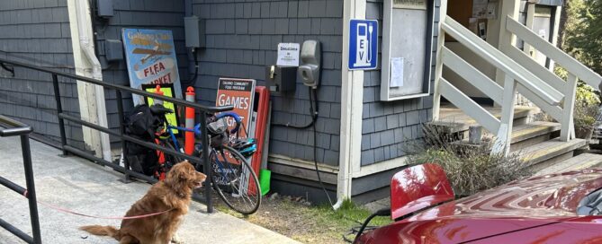 Red EV charging at a community hall with golden retriever dog looking on